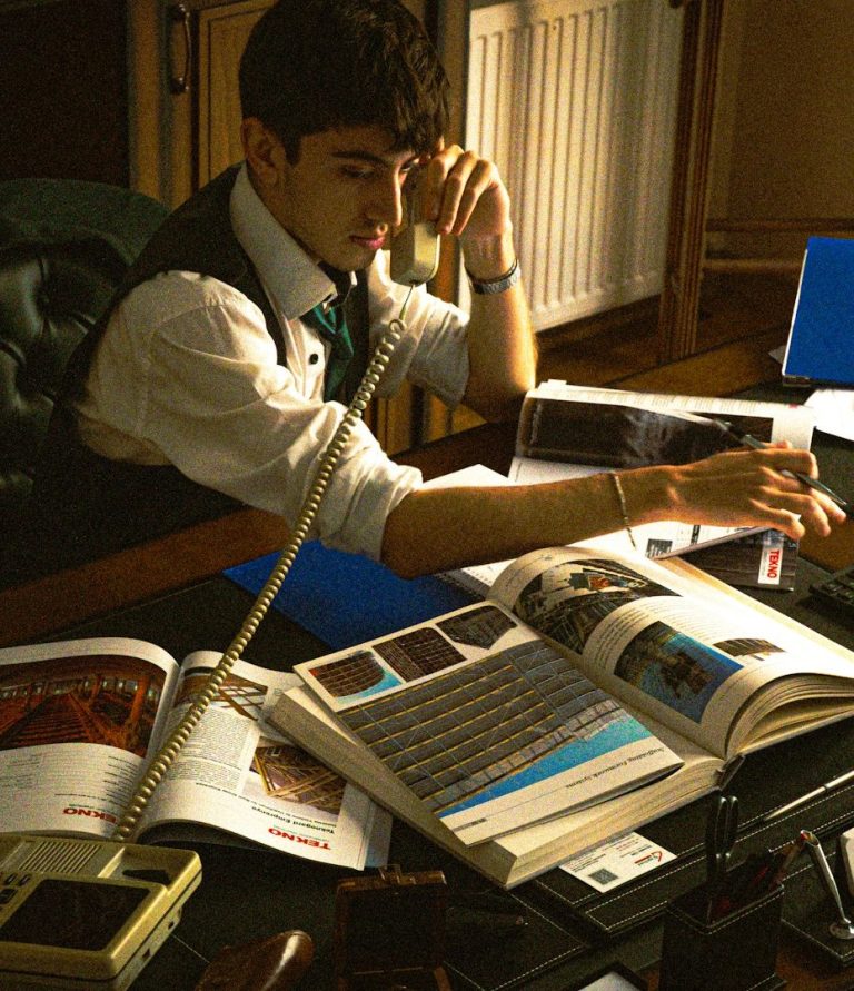 A man in a vest sits at a desk, conducting tax research while on the phone with a client.